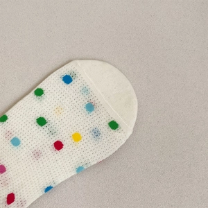 Close-up of white mesh socks with colorful polka dots showing breathable texture