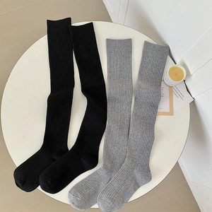 Detail of ribbed knit over-knee socks in black and grey on a decorative table