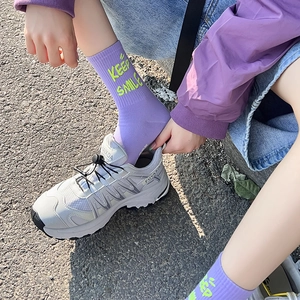 Dettaglio di calze viola con scritta Keep Smile abbinate a sneaker bianche all'aperto