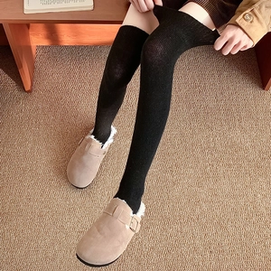 Detail of black ribbed over-knee socks with warm knitted texture for winter