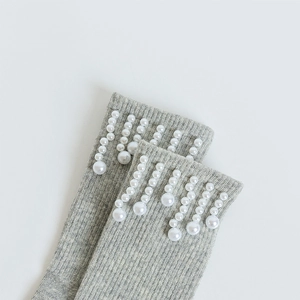 Gros plan de chaussettes grises côtelées avec perles blanches élégantes sur le bord