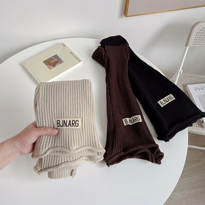 Detailed knit texture of beige, brown and black leg warmers with vintage brand labels