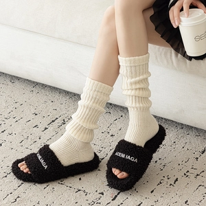 Gros plan sur des jambières en tricot blanc cassé avec des mules noires en peluche