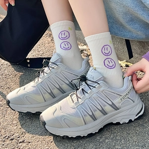 Sneakers retrò bianco sporco con calzini smiley su un terreno esterno neutro