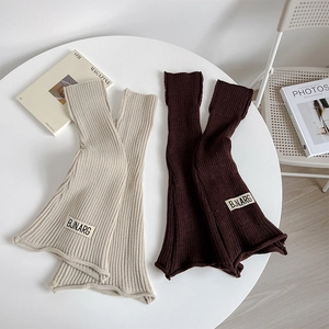 Detail of ribbed knit leg warmers with flare hems and decorative fabric label