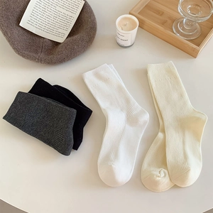 Flat lay of ribbed mid-calf cotton socks in neutral colors with autumn accessories