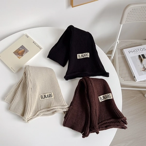 Detail of ribbed knit leg warmers in black, beige, and brown with retro fabric tags