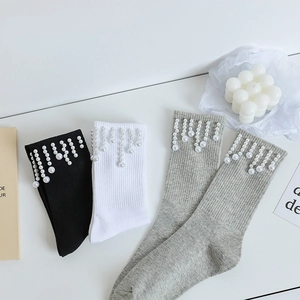 Détail de chaussettes en coton avec perles suspendues en blanc, noir et gris élégant