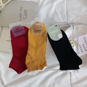 Détail de chaussettes en coton avec bordure en dentelle blanche, rouge, jaune et noir