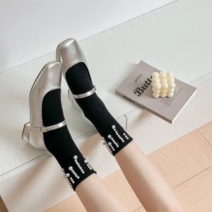Détail de chaussures Mary Jane argentées avec chaussettes noires ornées de perles blanches chic
