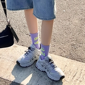 Dettaglio di calze in cotone viola con scritta Keep Smile e sneakers retrò stile street