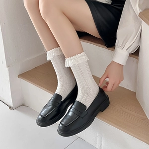 Close-up of white cable knit Lolita socks with lace trim and black leather loafers