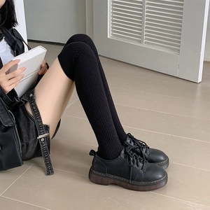 Detailed texture of black knit over-the-knee socks paired with platform shoes