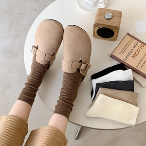 Detail of khaki suede mules styled with brown ribbed mid-calf socks and color set