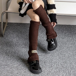 Detailed close-up of dark brown cable knit leg warmers with a stylish BJN.ARG fabric label