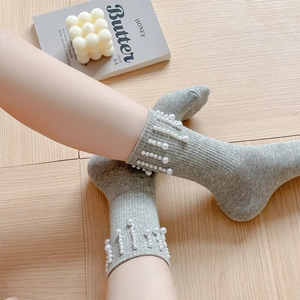 Détail de chaussettes en maille côtelée gris clair ornées de perles blanches élégantes
