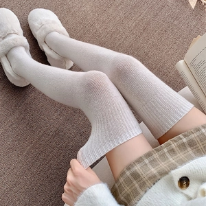 Close-up of white cable-knit over-the-knee socks with textured vertical patterns