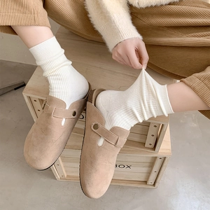 Close-up of khaki suede clogs with adjustable metal buckle and white ribbed cotton socks