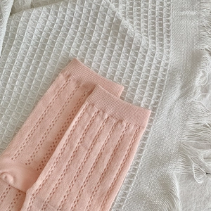 Detail of pink knitted five-finger socks with breathable hollow mesh patterns on a soft blanket