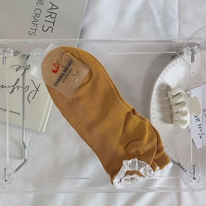 Détail des chaussettes en tricot jaune gingembre avec bordure en dentelle blanche