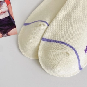 Dettaglio di calzini in cotone bianco panna con strisce viola e trama a lettere