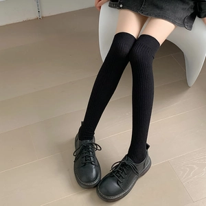 Thigh-high black ribbed knit socks for women paired with black leather shoes