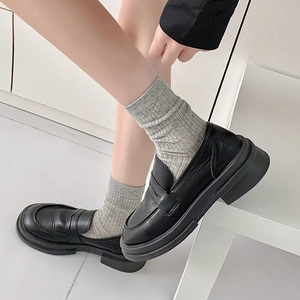 Nahaufnahme schwarzer Plateau-Loafer kombiniert mit grauen vertikal gestreiften Socken