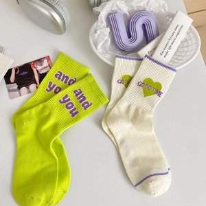 Dettaglio di calze in maglia a coste con ricamo smiley e palette verde neon