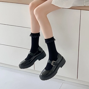 Detail of black patent leather Mary Jane shoes with thick soles and lace trim socks