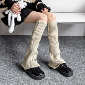 Detailed macro of beige chunky knit leg warmer with vintage tag and ribbed texture