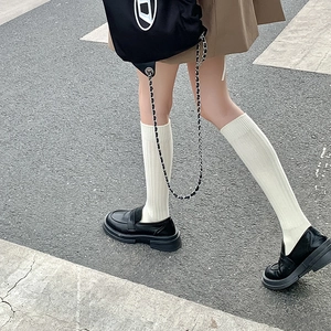 Primer plano de calcetines altos blancos acanalados con mocasines negros de plataforma