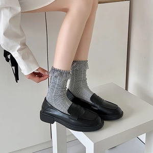 Detail of grey knitted Lolita socks with lace trim paired with black leather loafers