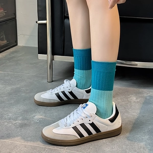 Detailed macro view of blue gradient ribbed crew socks paired with white athletic shoes