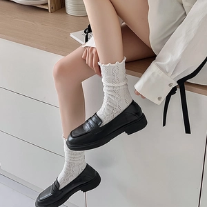 Détail de chaussettes blanches à volants ajourées avec mocassins noirs de style JK