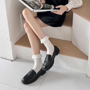 Close-up of white Lolita socks with cable knit texture and double-layered lace trim