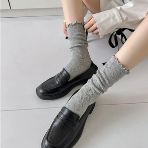 Détail de chaussettes gris clair à motif ajouré avec bords ondulés et maille fine