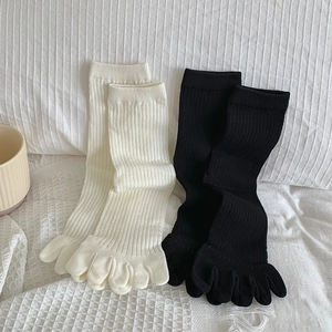 Detailansicht von gerippten Baumwoll-Zehensocken in Creme und Schwarz auf weichen Decken