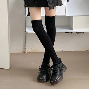 Thick black knitted over-the-knee socks with ribbed texture for a slimming leg effect