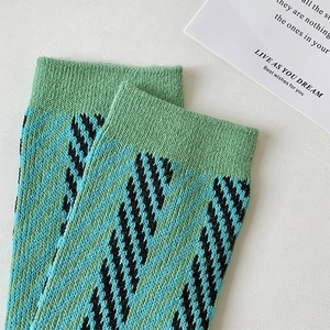 Detail showing the ribbed cuff and green blue geometric knit patterns of the cotton sock