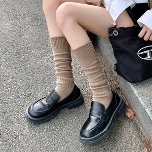 Detalle de calcetines marrones de punto elástico con mocasines negros de plataforma