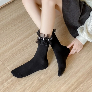 Detail of black crew socks with layered mesh ruffles and hand-sewn white pearls