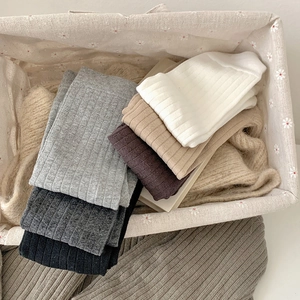 Close-up of ribbed cotton crew socks in neutral tones stacked in a fabric basket