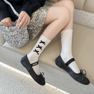 Détail de chaussettes hautes blanches en tricot avec trois nœuds noirs décoratifs