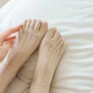 Macro detail of breathable hollow mesh pattern on cream-colored cotton five-finger socks