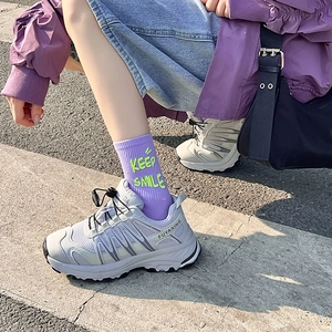Dettaglio di calze viola con scritte verde neon e sneaker bianche e grigie massicce