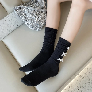 Vue détaillée de chaussettes mi-hautes noires avec nœuds blancs et froufrous tendance
