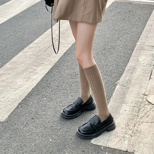 Primer plano de calcetines altos de canalé caqui con mocasines negros de plataforma clásicos
