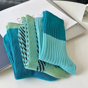 Detail of teal and green knit crew socks with ribbed, striped, and houndstooth patterns