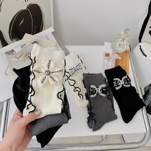 Detail of sweet knit socks with ruffle trim and 3D floral bow accents in white and grey
