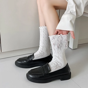 Gros plan de chaussettes blanches en maille pointelle à volants avec mocassins noirs